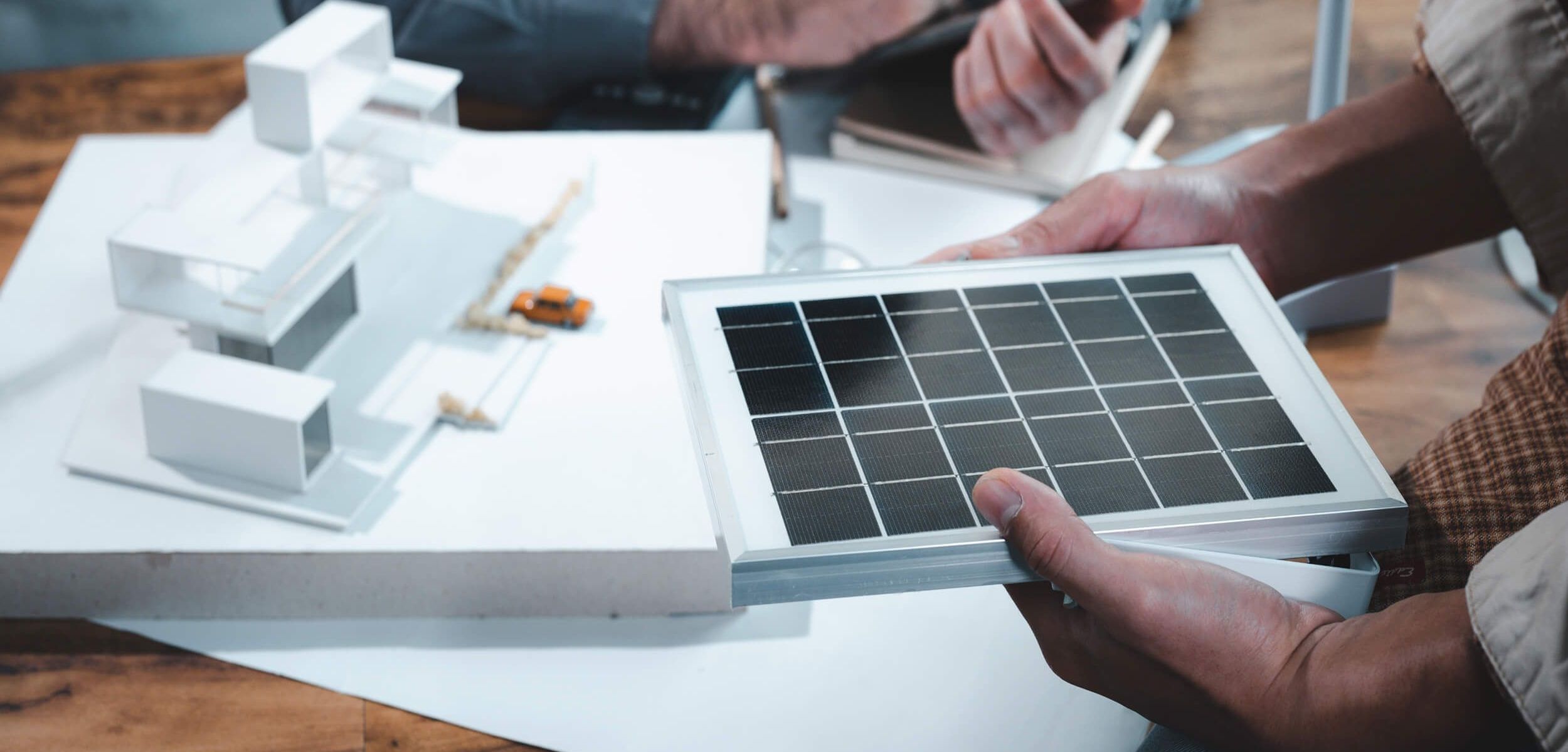 zwei Personen, die an einem Tisch sitzen, auf dem ein Modell eines Haues steht